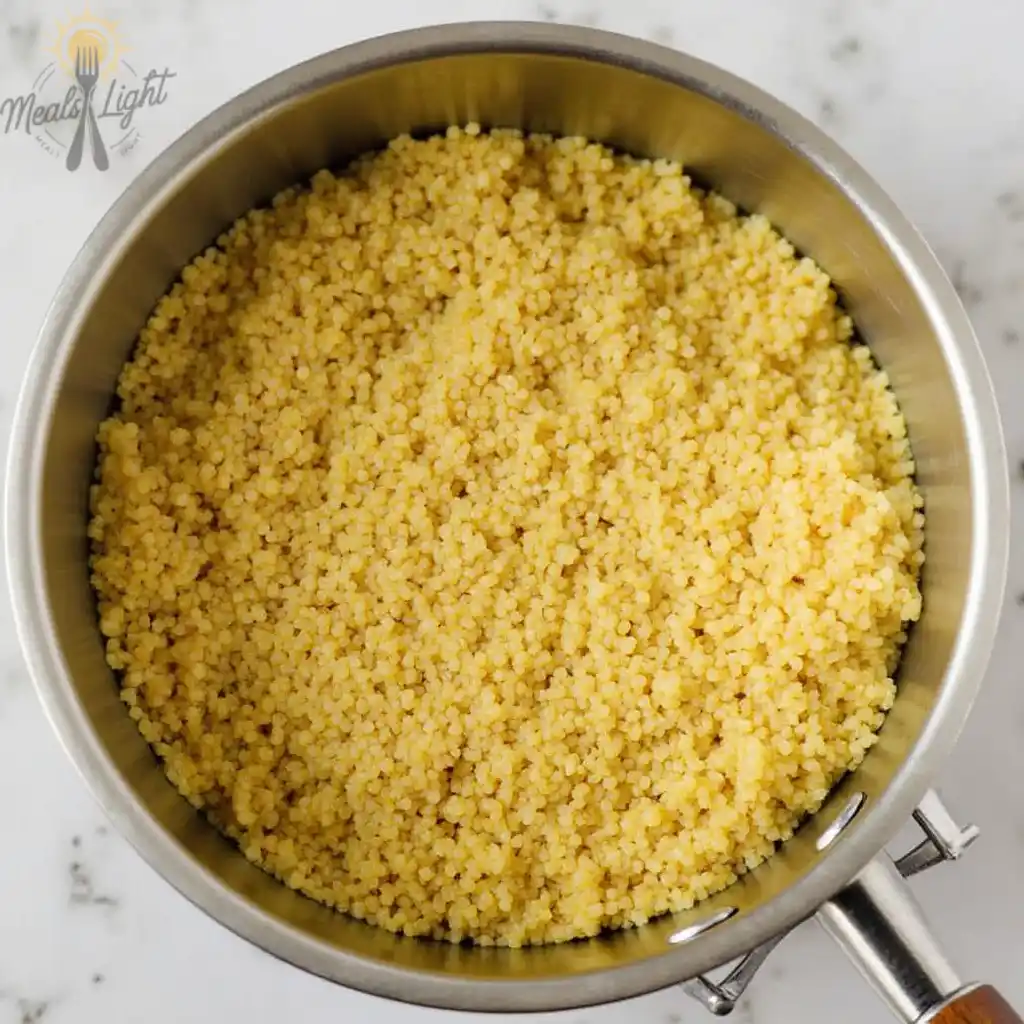 A pot filled with cooked quinoa on a marble countertop.