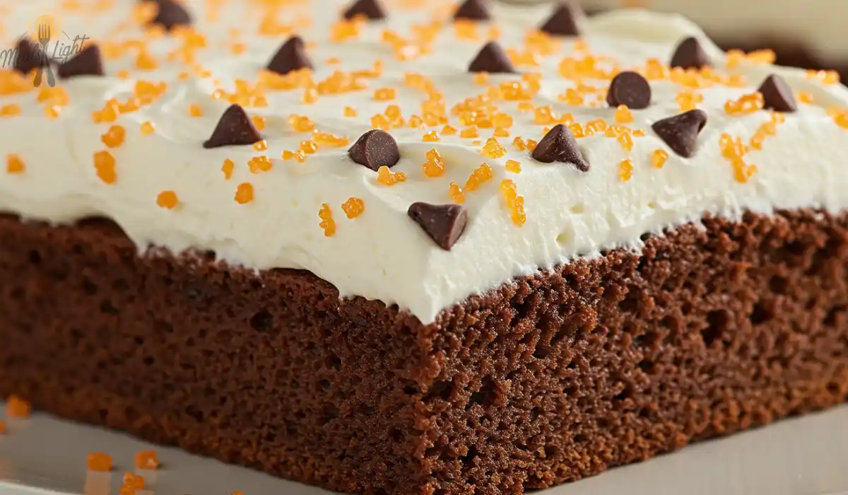 A rich chocolate Kefir Sheet Cake topped with creamy white frosting, garnished with chocolate chips and orange sugar crystals.